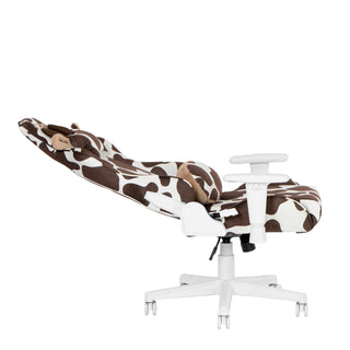 The cow gaming chair in brown shown in a full 150 degree recline against a white background. The brown cow gaming chairs has white hardware such as 2d armrests, base, wheels and casters. 